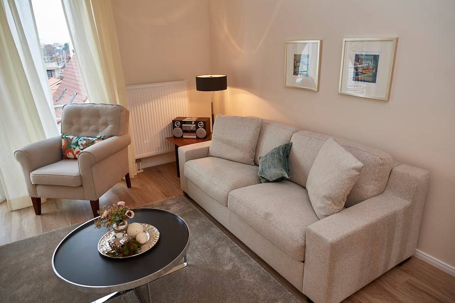 Das Wohnzimmer mit Sessel und Sofa, das sich in ein Bett mit hohem Schlafkomfort verwandeln lässt.