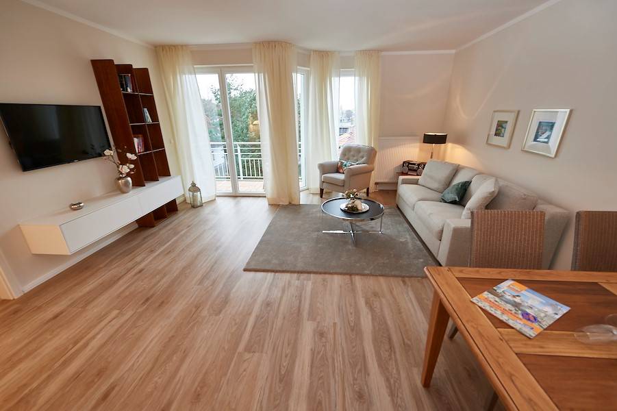 Behaglich und hell ist das Wohnzimmer mit einem großen Flachbildschirm