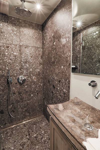 Das zweite Luxusbad ist ebenso mit einer Regendusche und Marmor versehen
