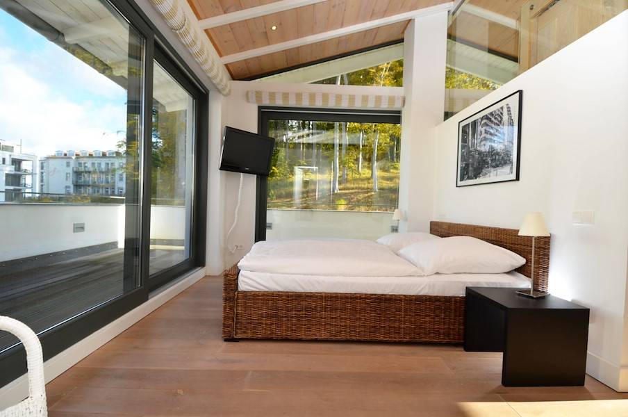 Schlafzimmer mit Doppelbett und Flachbildschirm, viel Licht und Ausgang zur Terrasse