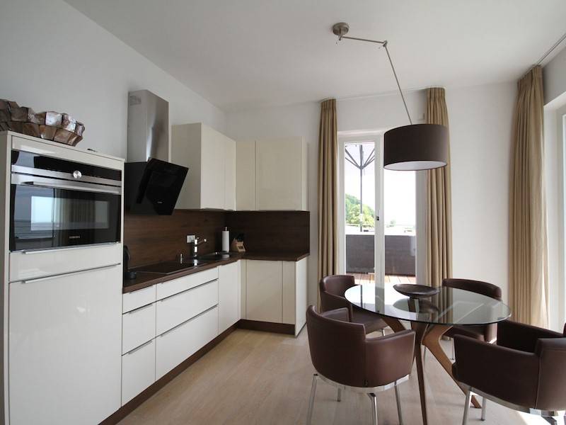 Die moderne Küche mit gemütlichen Lederstühlen vor dem Fenster mit Meerblick
