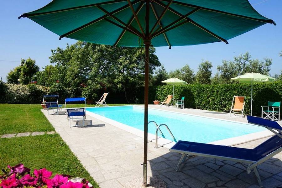 Der windgeschützte Pool mit Sonnenliegen und Sonnenschirm